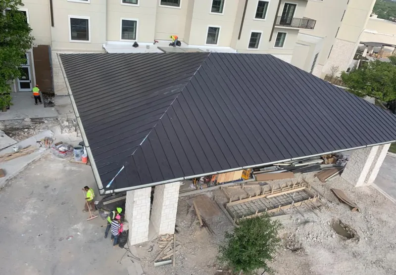Metal roofing installation team working on a commercial building in Troy